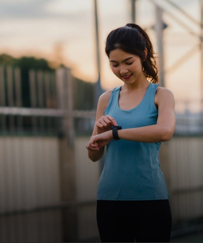 ランニングの合間にスマートウォッチを見る女性