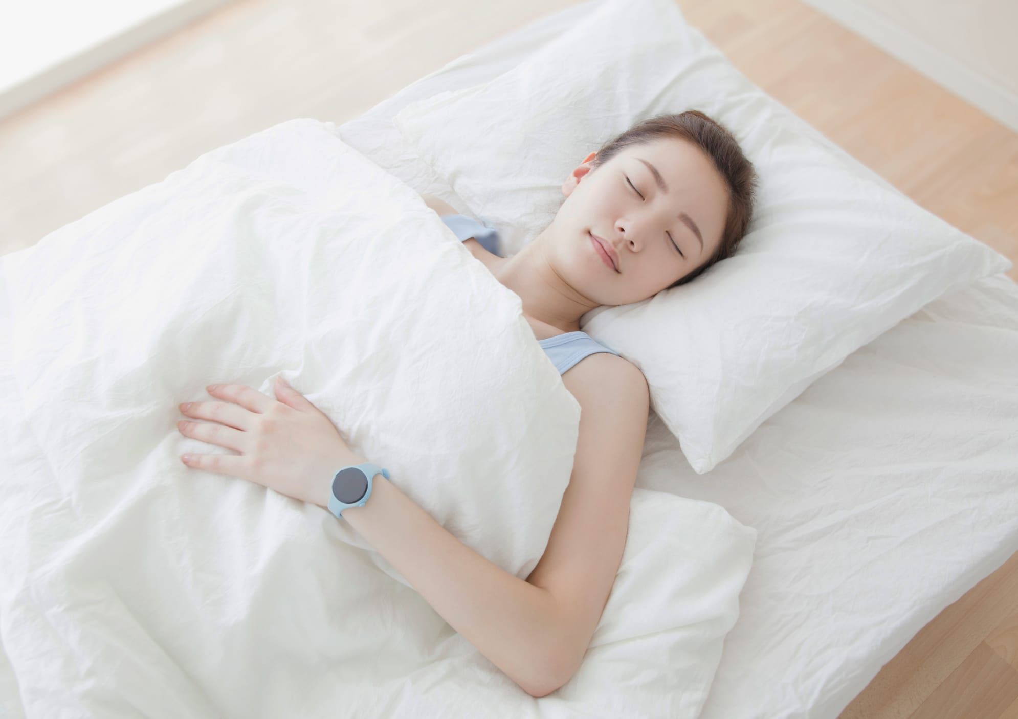 腕にスマートウォッチをつけて眠る人